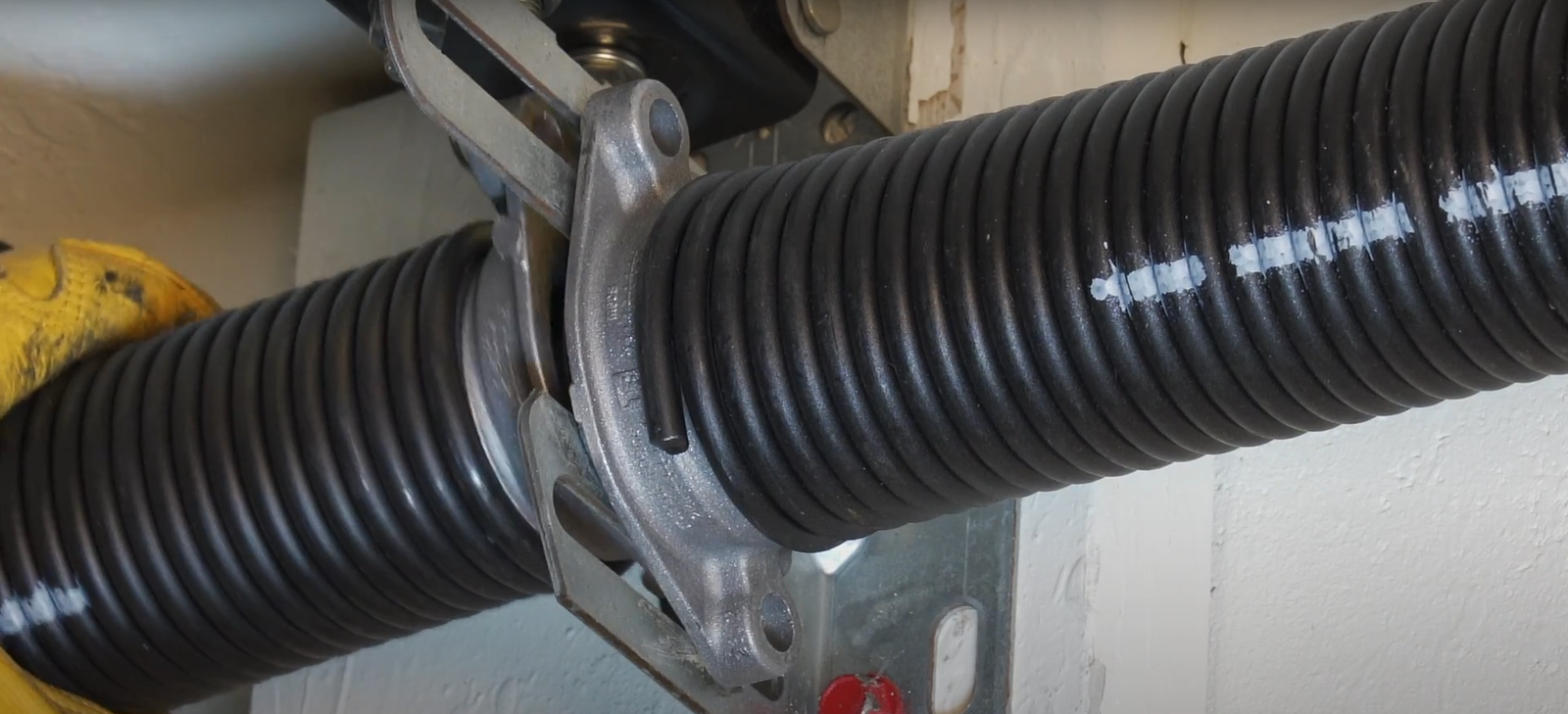 A close-up of a garage door spring mounted on the wall.