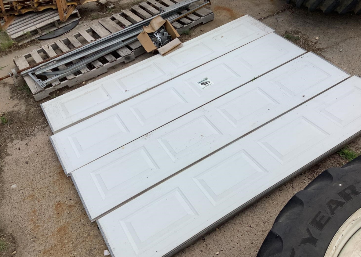 A skilled technician from Jupiter FL Garage Door Repair Services kneeling next to a residential garage door, effectively replacing a damaged garage door panel with precision tools, highlighting professional garage door panel repair services.